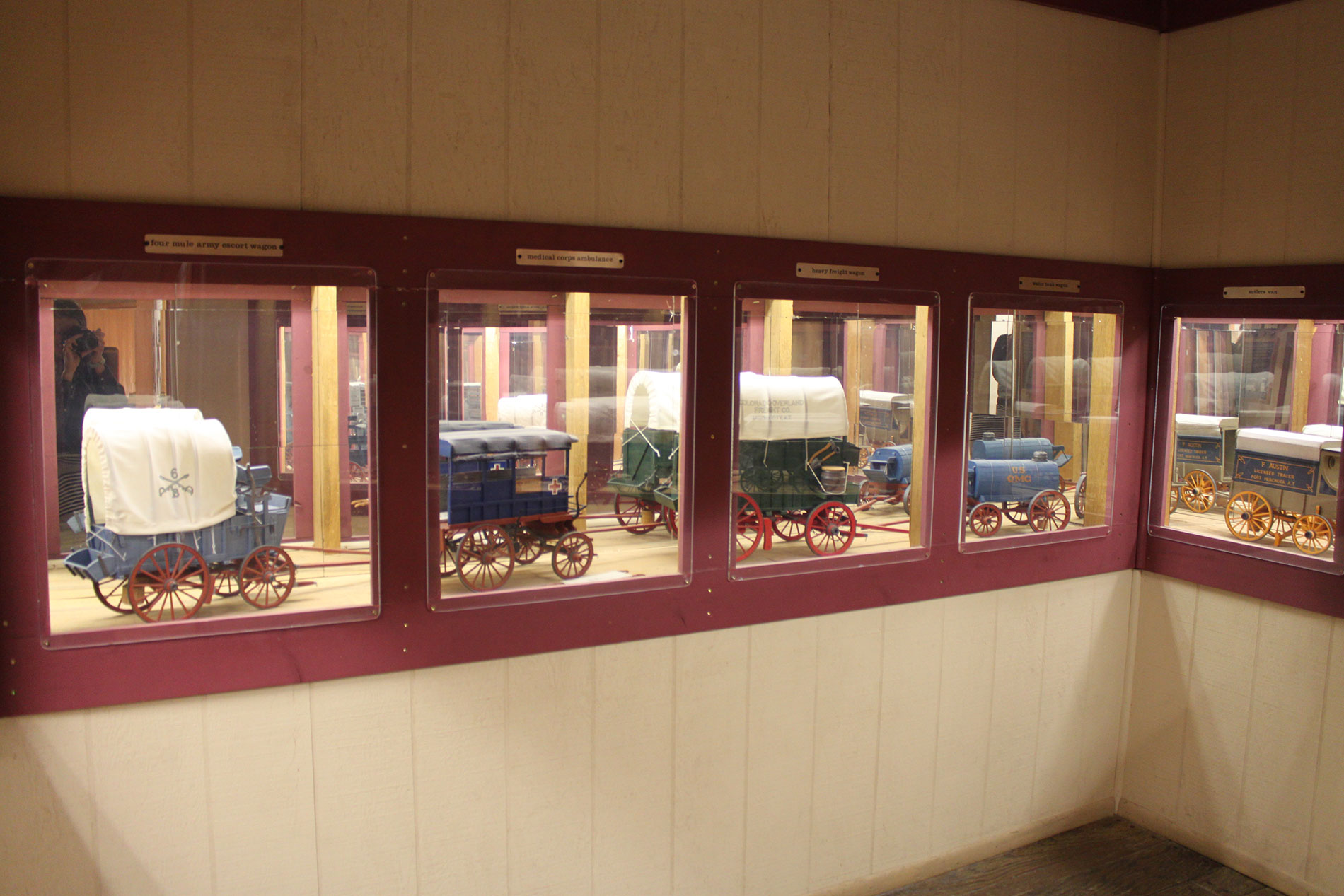 A museum collection of several replica wagons inside a glass structure.